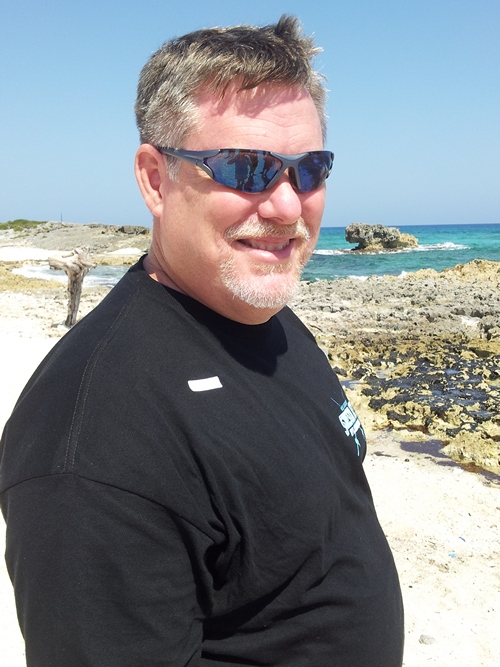 Profile photo of man wearing sunglasses standing on a beach